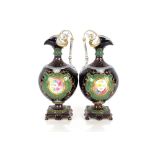 A pair of Sevres style ewers, having floral spray decorated central panels on apple green and cobalt