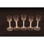 Five 18th Century drinking glasses of various sizes all having cotton twist stems on circular spread