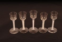 Five 18th Century drinking glasses of various sizes all having cotton twist stems on circular spread