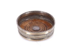 A silver coaster with turned wooden base, having central boss with engraved family crest,
