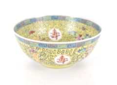 A Chinese yellow ground bowl, profusely decorated flowers and symbols within Greek key border, 22.