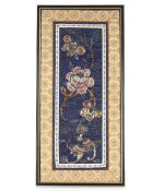 A framed and glazed Chinese embroidered section of a mandarin's cloak, decorated flowers and