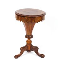 A Victorian walnut trumpet shaped sewing table, the circular top opening to reveal a fitted