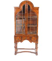 A pair of 1930's walnut display cabinets, having domed tops and enclosed by glazed panel doors, each