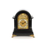 A large 19th Century ebonised mantel clock, the arched case supporting an ornate foliate brass