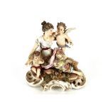 A small 19th Century German porcelain figure group, depicting maiden and cherubs, on a rock work