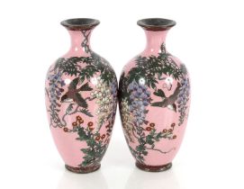 A pair of Oriental cloisonné baluster vases, profusely decorated birds and foliage on a pink ground,