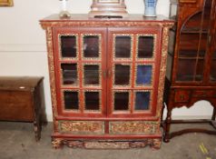 An Oriental lacquered display cabinet, the interior shelves enclosed by a pair of glazed panel doors