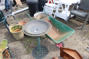 A plastic bird bath together with a metal wheelbar