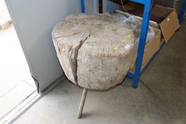 A rustic chopping block raised on three legs