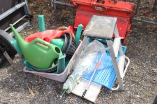 A quantity of various watering cans, seed spreader