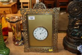 A mantel timepiece in ornate brass easel frame