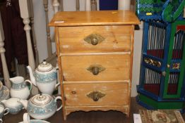 A small pine three drawer miniature chest of drawe