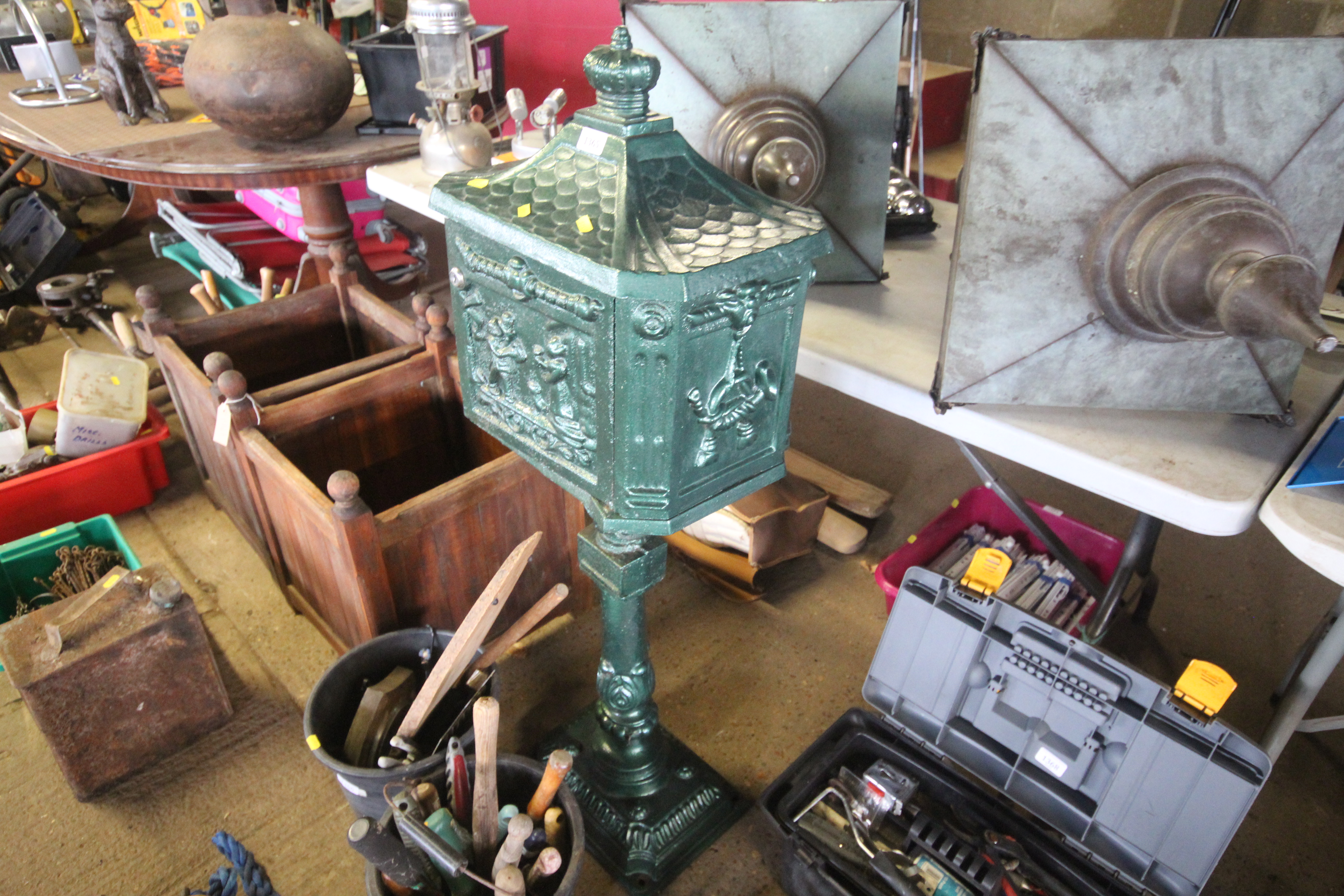 A large ornate green painted letter box on stand,