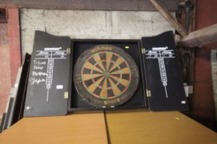 A Winmau dart board containing in a wooden two doo