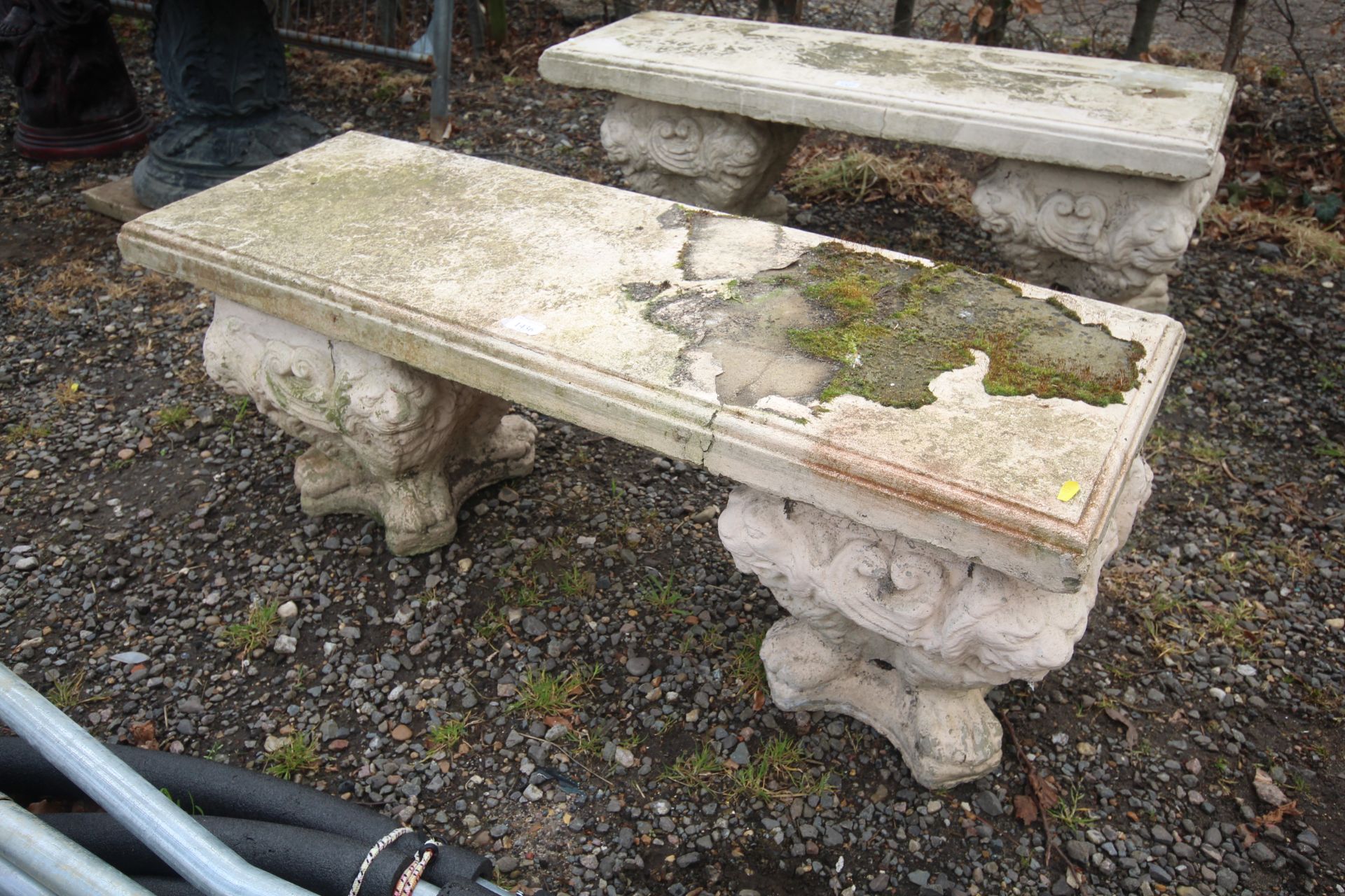 A painted concrete garden bench raised upon a pair