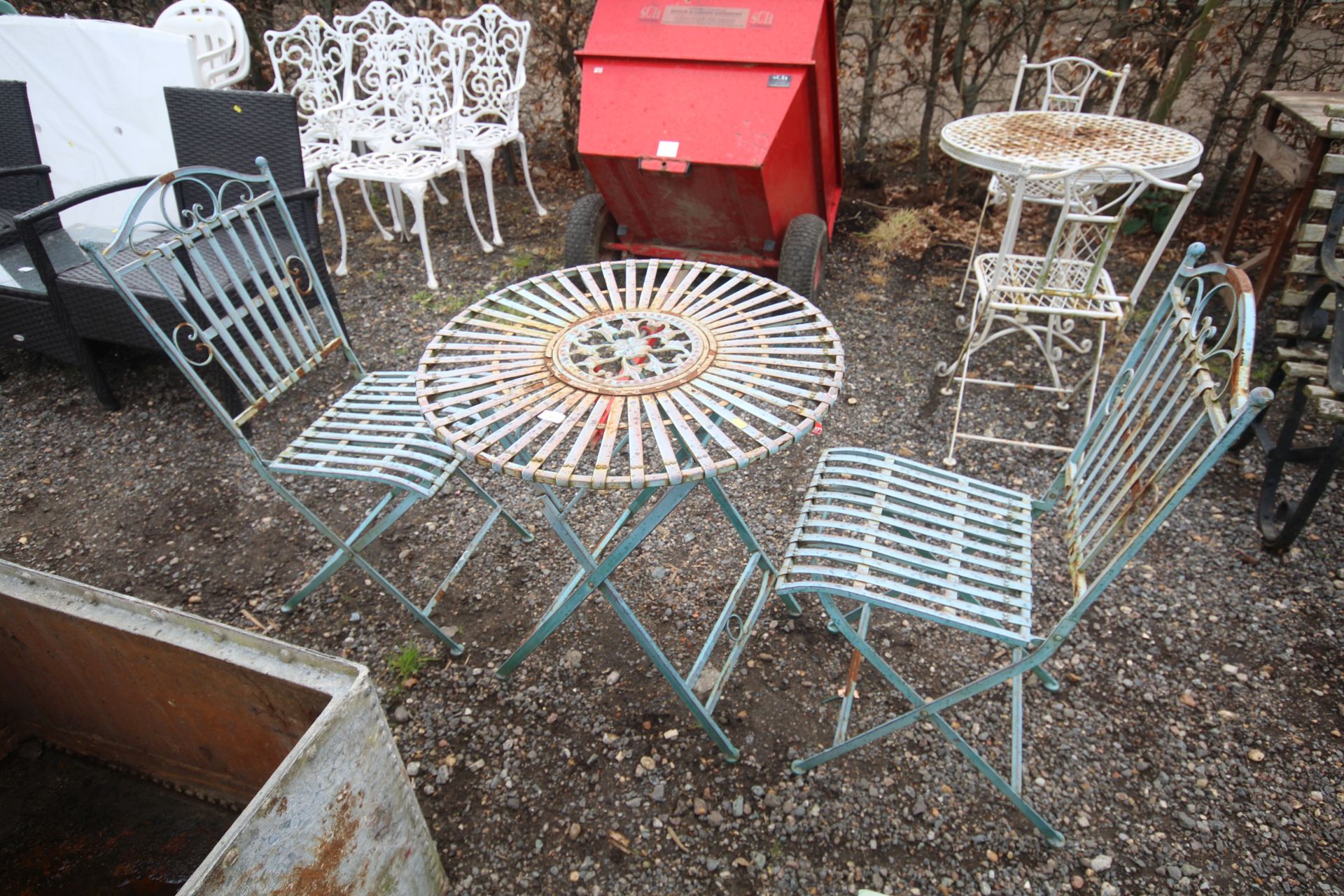 An ornate folding metal bistro table and pair of m