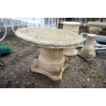 An ornate painted concrete garden table set onto a