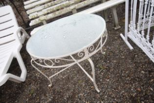 A circular wrought metal garden table with glass t