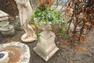 A painted concrete garden urn raised on three tier