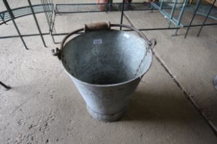A galvanised bucket with wooden and metal swing ha