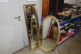 An oval gilt framed and bevel edged wall mirror an
