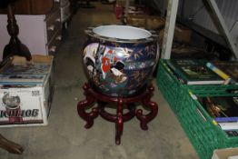 An Oriental goldfish bowl on wooden stand