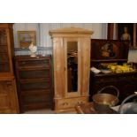 An antique stripped pine mirrored door wardrobe