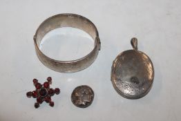 A silver hinged bangle; a white metal locket; a si