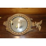 A circular gilt framed wall mirror with eagle surm