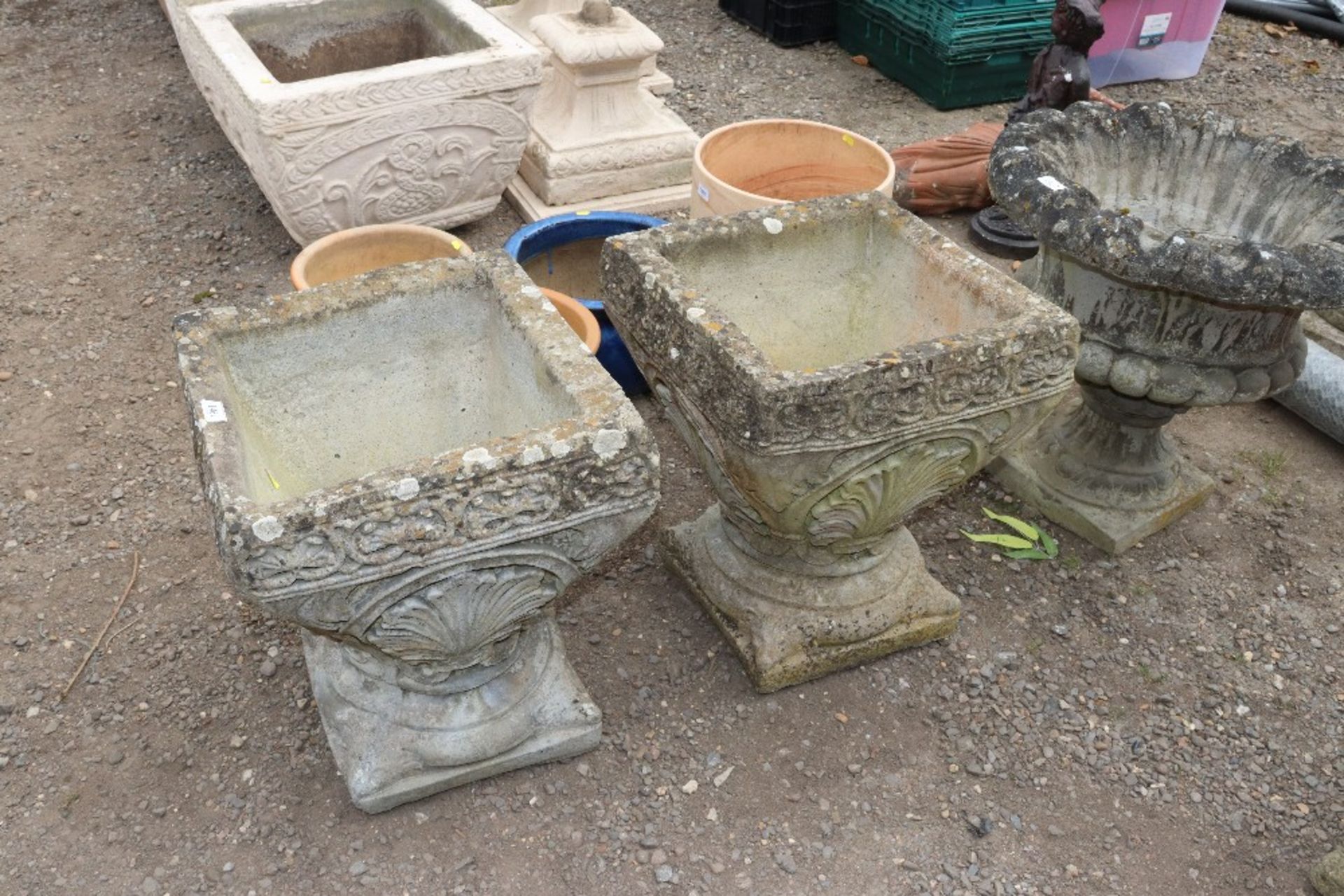 A pair of concrete ornate planters raised on plint