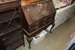 An oak bureau fitted two drawers raised on cabriol