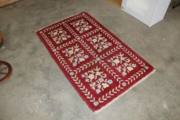 An approx. 5' x 3' red floral patterned rug