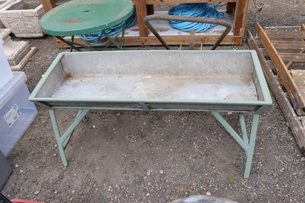 A galvanised trough on painted metal stand