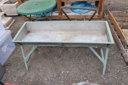 A galvanised trough on painted metal stand