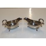 A pair of silver sauce boats with scroll handles,