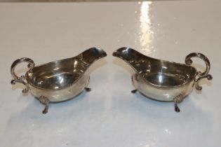 A pair of silver sauce boats with scroll handles,