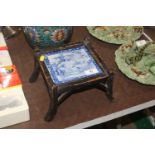 An antique stand with inset of blue and white tile