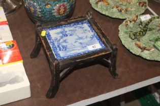An antique stand with inset of blue and white tile