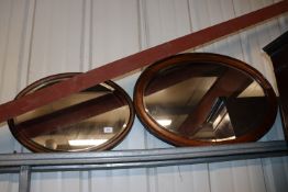 Two oval bevel edged wall mirrors contained in oak