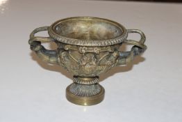 A bronzed twin handled pedestal bowl decorated wit