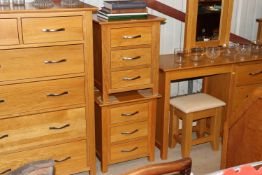 A pair of light oak three drawer bedside chests