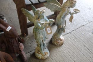 A cast iron statue of a standing fairy holding a b