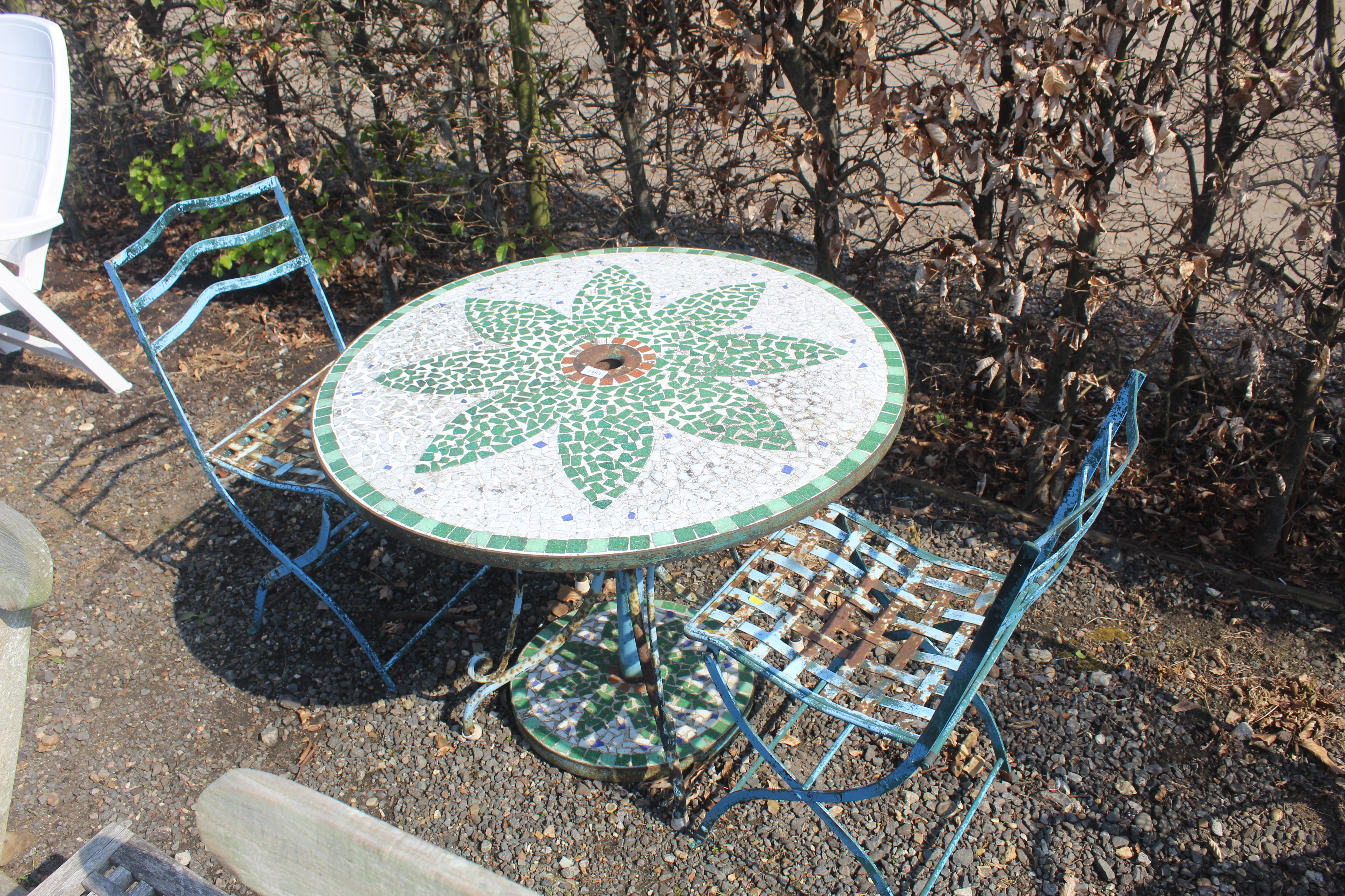 A mosaic patterned tile topped circular garden tab