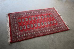 An approx. 5'7" x 3'2" red patterned rug