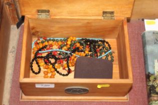 A wooden box of jewellery to include bead necklace