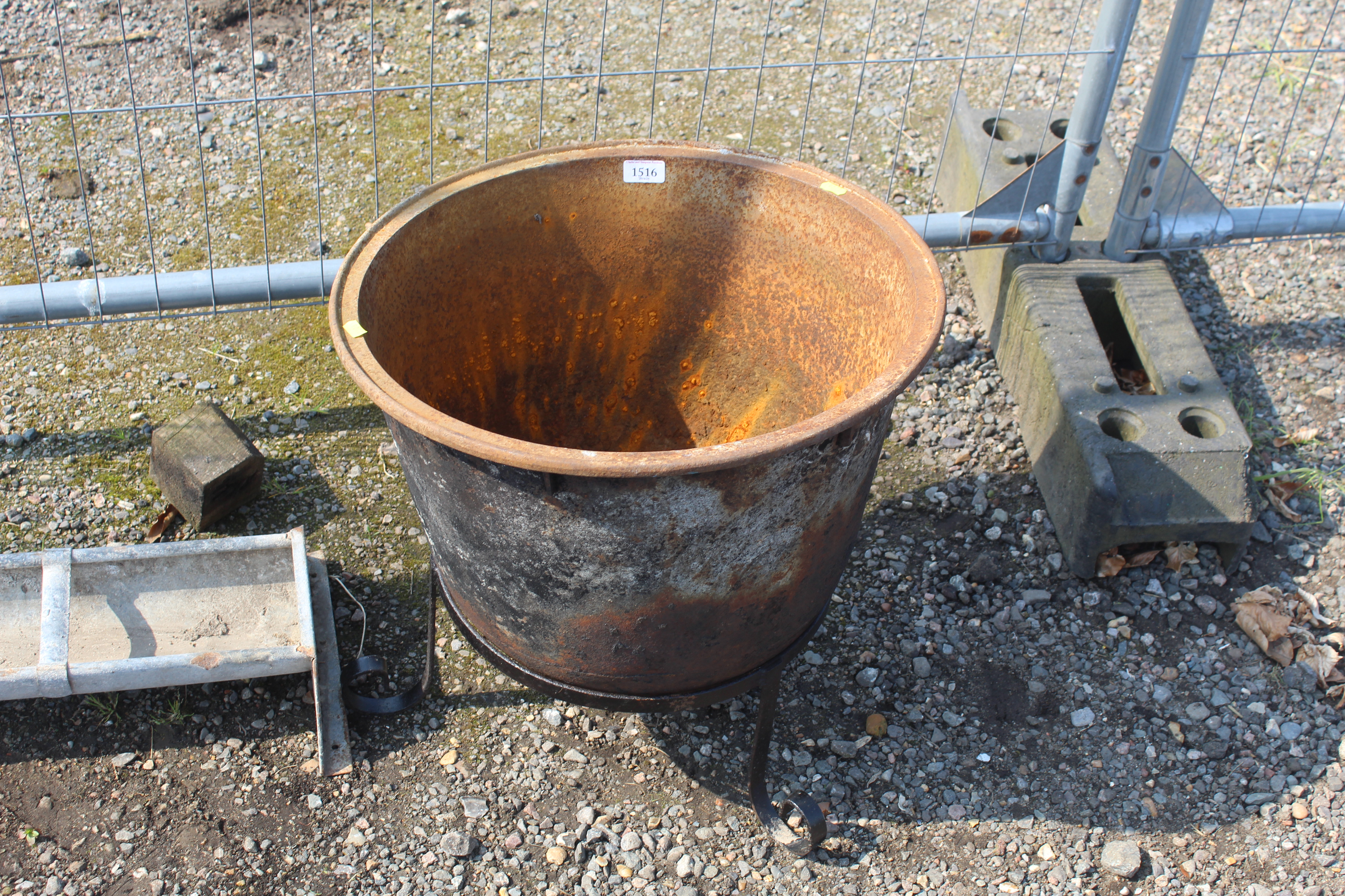 A circular cast iron cauldron on wrought metal sta