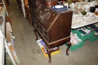 An oak bureau fitted two drawers, raised on cabrio