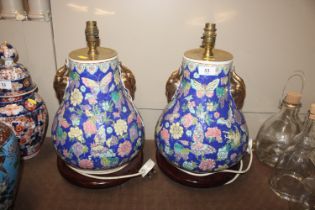 A pair of Oriental style ceramic table lamp bases with gilt rams head decoration on circular black