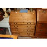 A stripped pine bureau fitted four long drawers